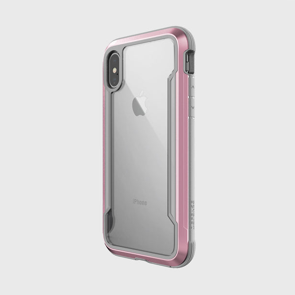 An iPhone X with a clear back and pink Raptic SHIELD bumper case displaying the Apple logo stands upright against a plain background, providing military-grade drop protection.