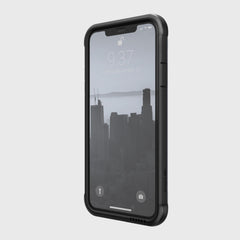 An iPhone 11 Pro Max is encased in a Raptic SHIELD black rugged case with drop protection, showing the time 9:37 and date Tuesday, September 26. The cityscape wallpaper complements its sleek aluminum alloy design and towering buildings.
