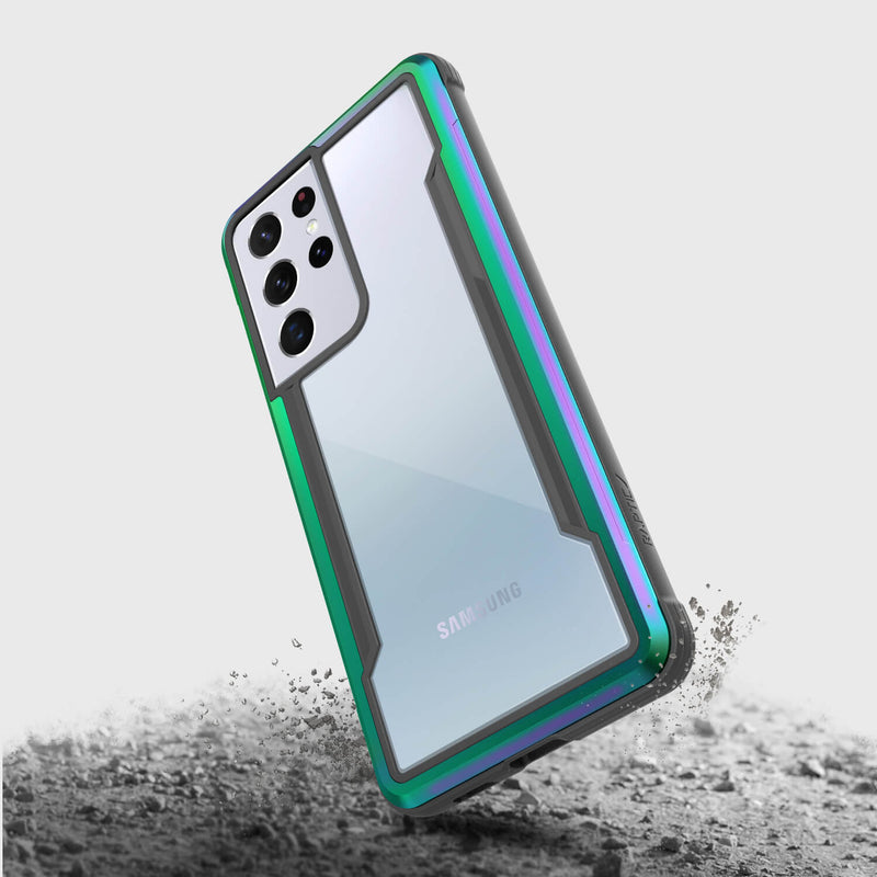 The Samsung Galaxy S21 Ultra encased in the X-Doria Raptic Shield Iridescent phone case hovers above a dusty surface, blending style with military-grade protection to ensure durability on any adventure.