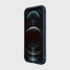 The iPhone 12, featuring a dark abstract wallpaper, is encased in Raptic's SHIELD PRO MAGNET blue cover for drop protection, displayed against a plain background.