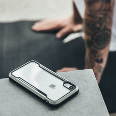 An iPhone SE/8/7 Case - SHIELD by Raptic on a table with a tattoo on it.