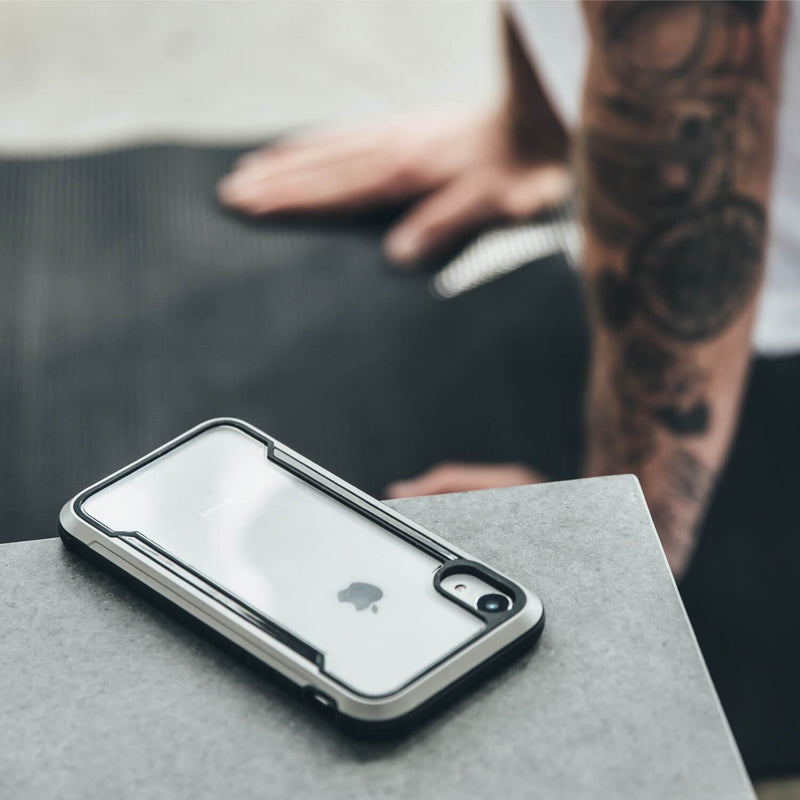 An iPhone SE/8/7 Case - SHIELD by Raptic on a table with a tattoo on it.