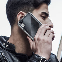 A person in a black leather jacket holds an iPhone XR with a Raptic LUX impact-resistant polycarbonate case to their ear.