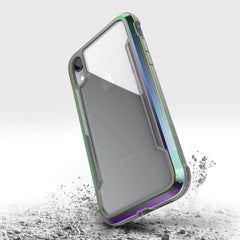 The iPhone XR Case - SHIELD by Raptic is showcased with a green metallic finish, surrounded by dust clouds, highlighting its military-grade drop protection and shock absorption.