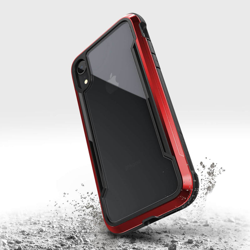 A rugged red and black iPhone XR case from Raptic, called SHIELD, lands on a surface, stirring up dust. It offers military-grade drop protection for durability and superior shock absorption against unexpected falls.