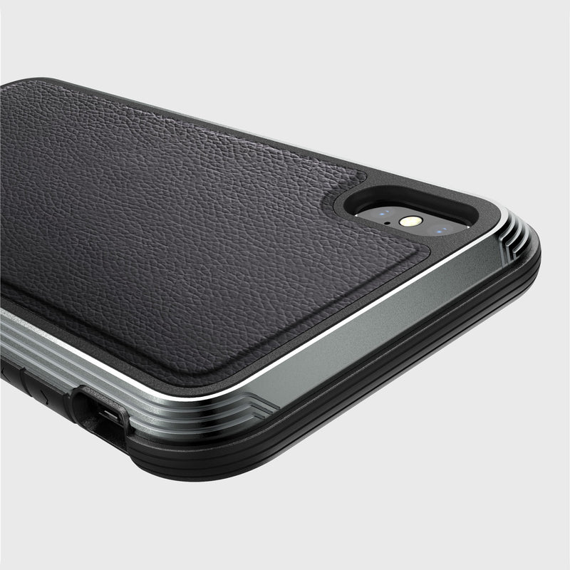 Close-up of an iPhone XS Max in the Raptic LUX case, showcasing a textured black leather-like back and durable machined aluminum edges, highlighting the impact-resistant polycarbonate around the rear camera.