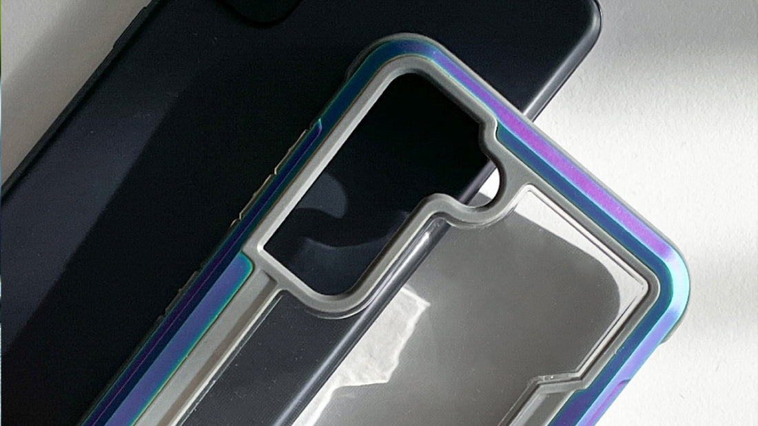 A black smartphone partially covered by a transparent phone case with a blue and purple edge, laid on a flat, white surface.