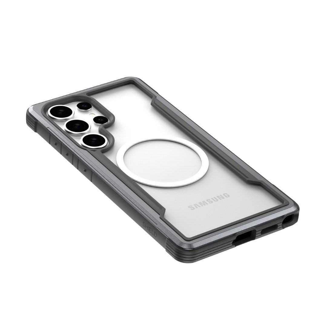 A clear and gray Raptic Samsung Galaxy S25 Case - SHIELD with a round MagSafe-like emblem and multiple lens camera cutout provides military-grade drop protection, all on a white surface.