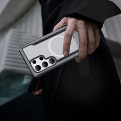 A person showcases a Samsung Galaxy S25 with four cameras, encased in a sleek Raptic SHIELD gray and white case featuring military-grade drop protection, against a blurred cityscape.