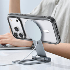 A person types as their iPhone 17, in the Raptic Shield Case by Raptic, charges securely on a horizontal metal MagSafe stand.