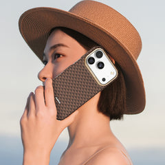 A person in a wide-brimmed hat holds the Raptic iPhone 17 Aramid Fibre Case - Skin-Origin, a MagSafe-compatible, ultra-light military-grade cover, to their ear as if making a call against a light sky background.
