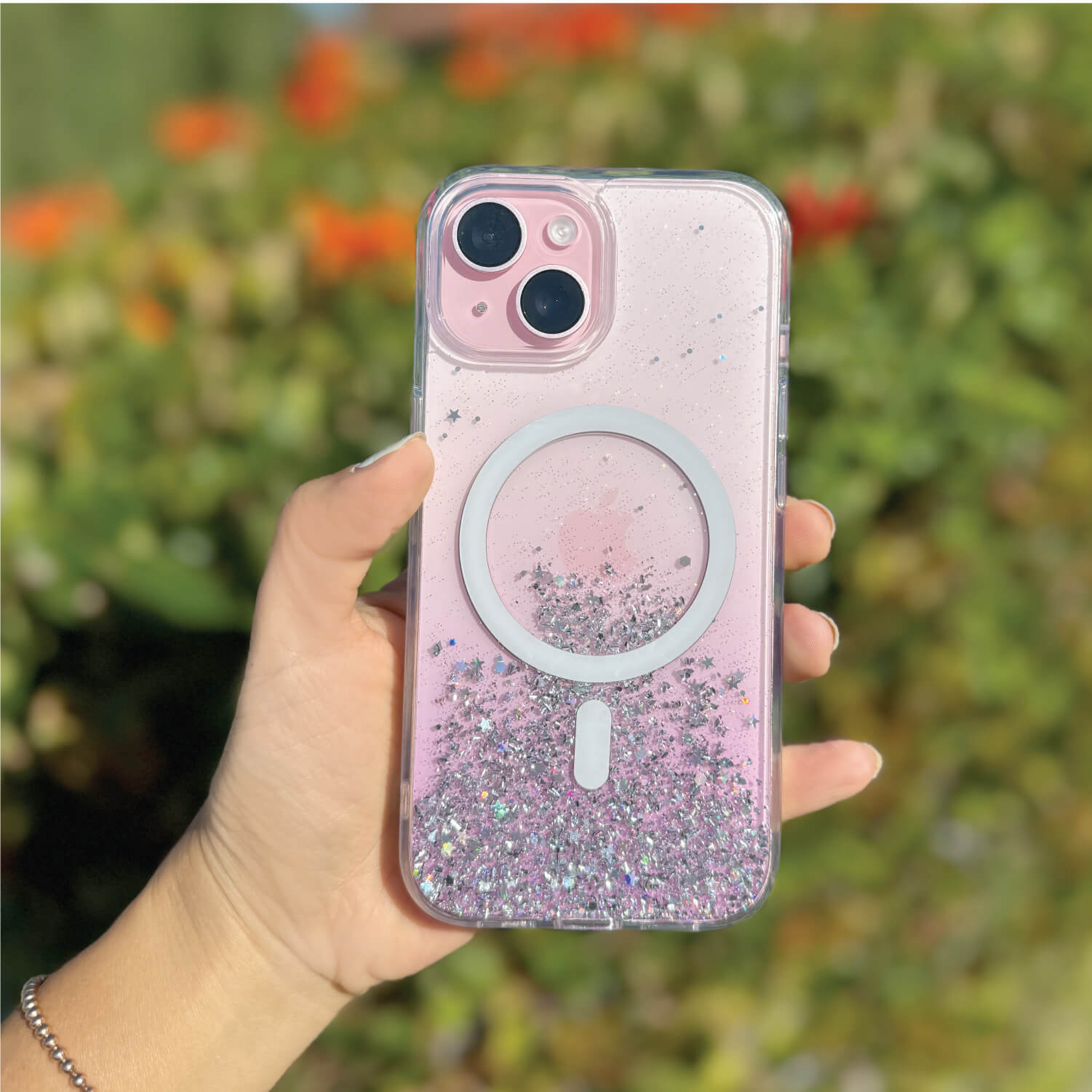 A hand holding a pink glitter iPhone 15 Starburst Glitter MagSafe Case - Bryten by Raptic featuring MagSafe technology.