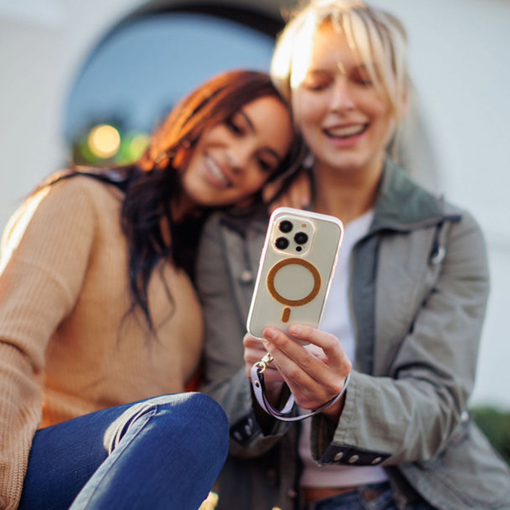 Two women are taking a picture with their iPhone 15 Pro, using the wireless charging and MagSafe feature of the iPhone 15 MagFx MagSafe Case - Bryten by Raptic.