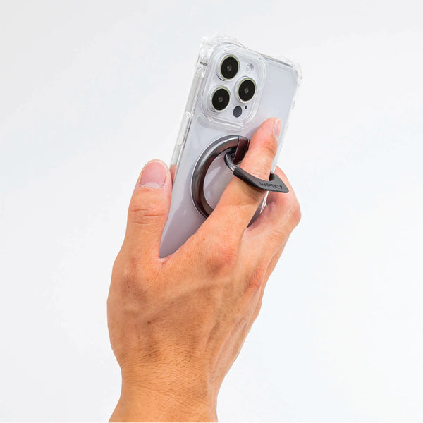 A person holding a Raptic MagSafe Ring Stand - Gunmetal-compatible phone with a ring stand.