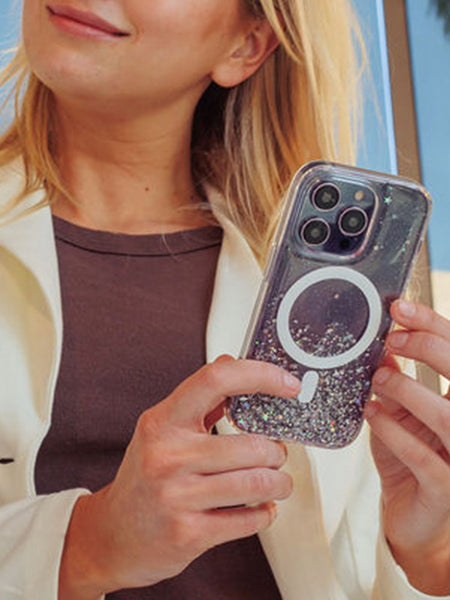 A woman holding a iPhone 15 Starburst Glitter MagSafe Case - Bryten by Raptic with a g on it.