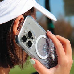 A woman wearing a golf hat while holding an iPhone 15 Starburst Glitter MagSafe Case - Bryten by Raptic that supports wireless charging.