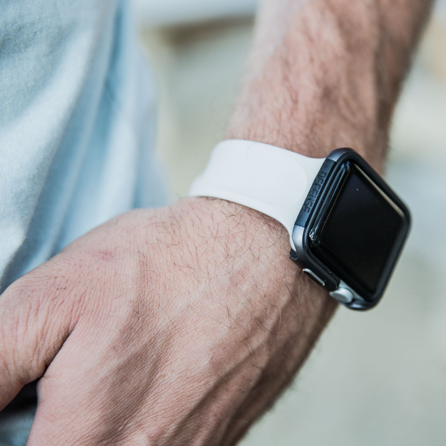 A man wearing a Raptic Apple Watch 44mm Case - EDGE with a white band, featuring a premium machined anodized aluminum bumper that protects it.