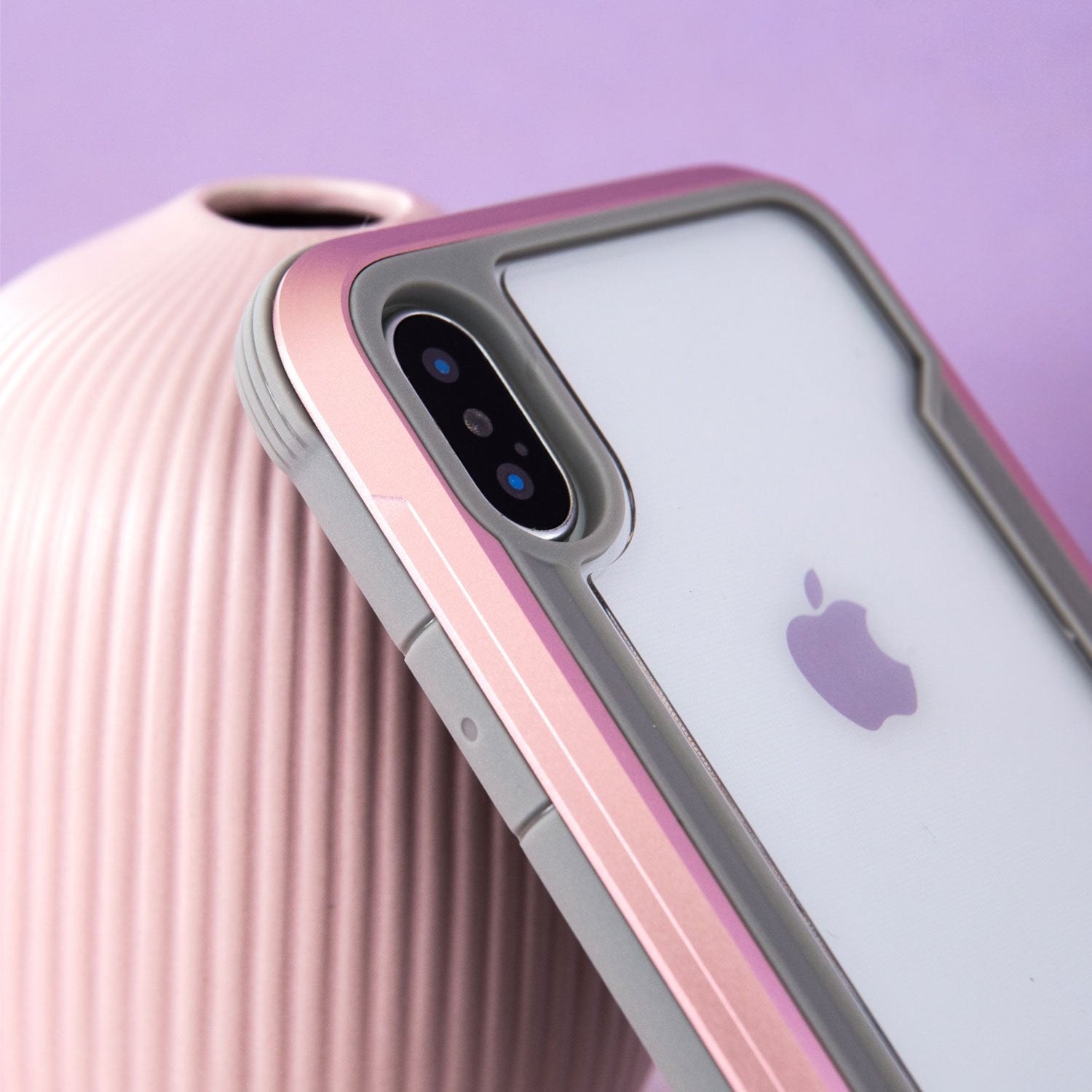 A pink Raptic Shield case on top of a vase, providing iPhone XS Max with drop protection.