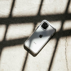 A white Raptic iPhone 11 Pro Case - AIR is laying on a concrete floor, ensuring drop protection.
