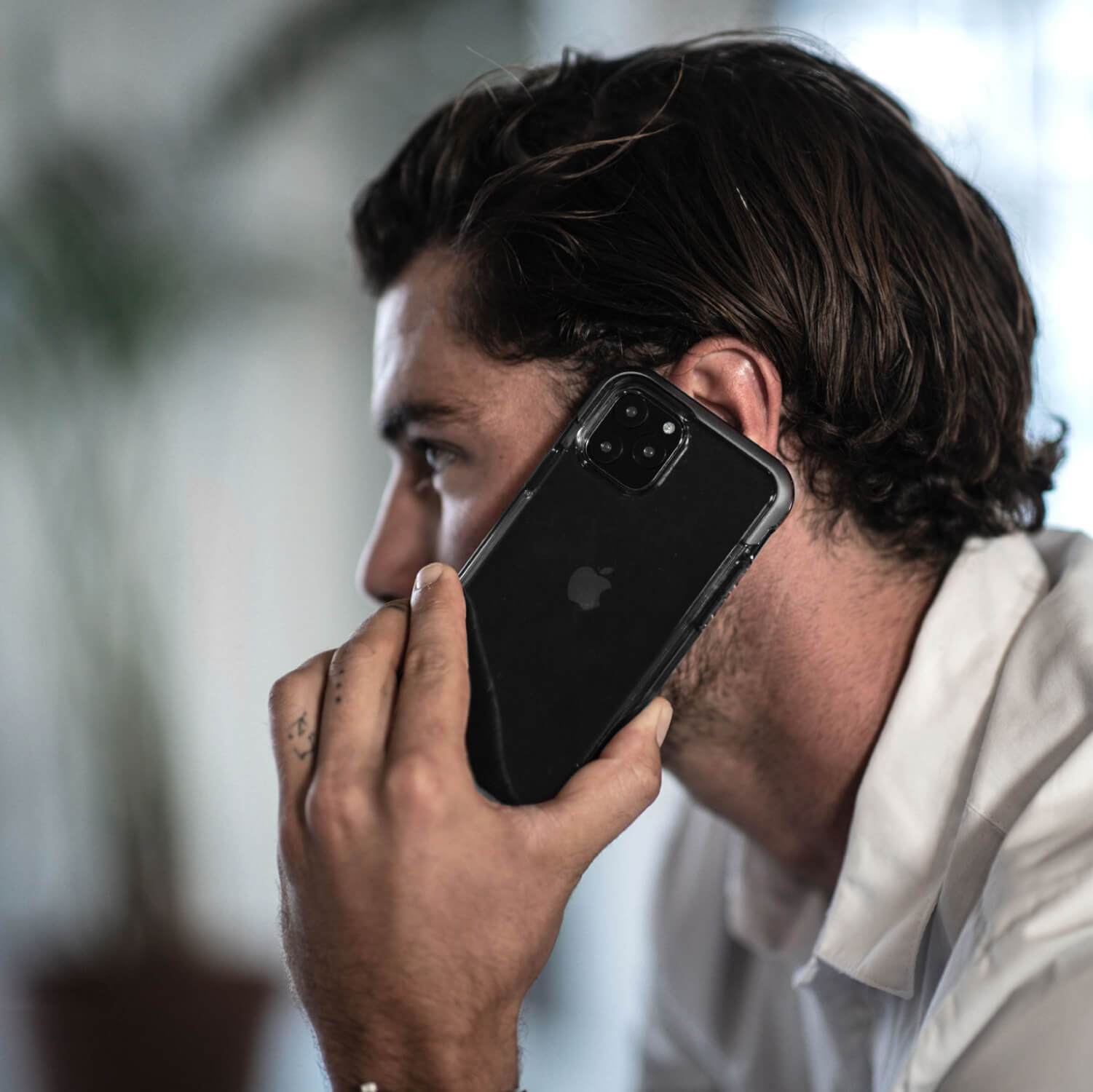 A man is talking on his Raptic Air-enabled iPhone 11 Pro Max while wearing a Raptic AIR iPhone 11 Pro Max Case providing 13 foot drop protection.
