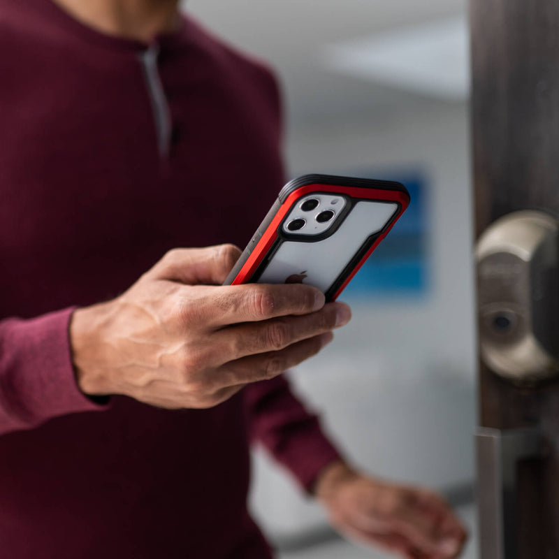 A man is holding his Raptic iPhone 12 Mini Case - SHIELD in front of a door.