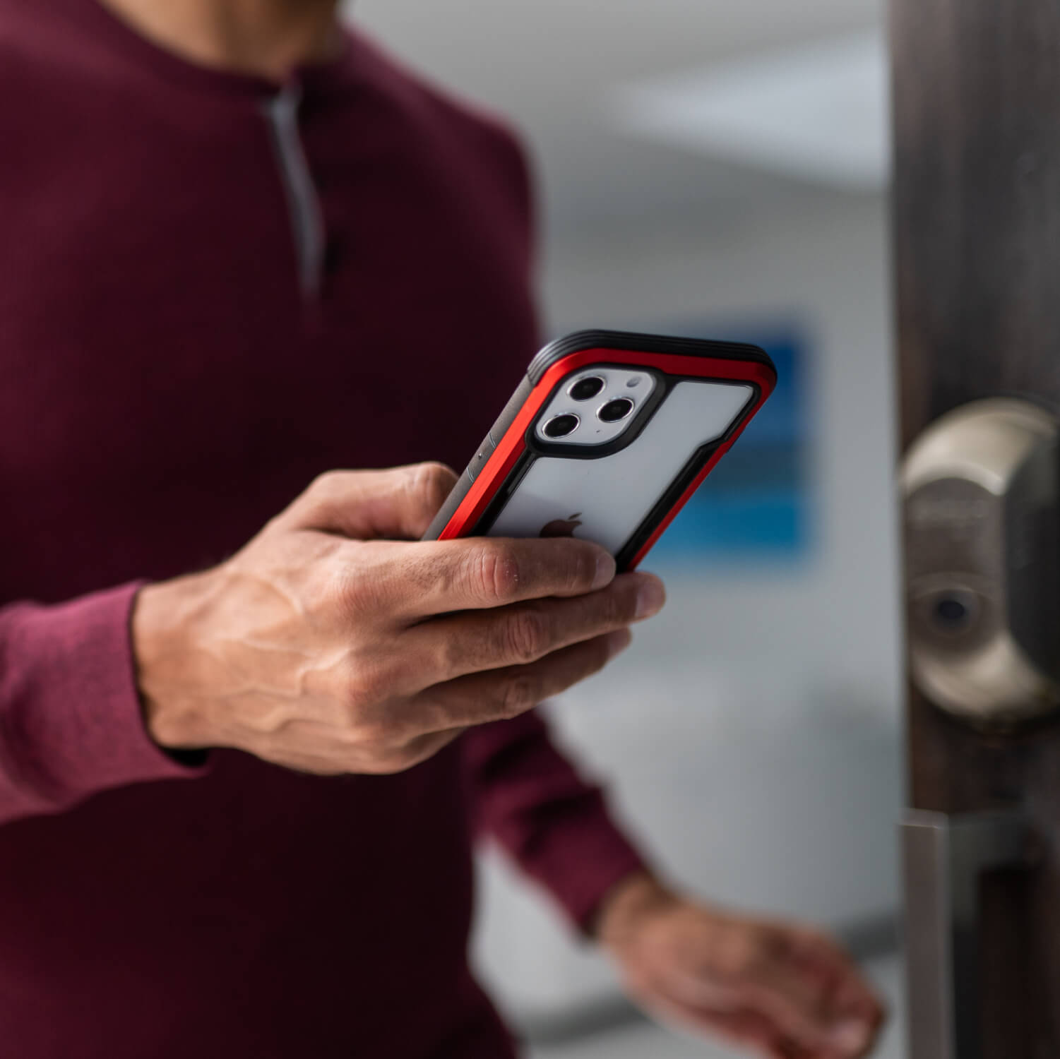 A man is holding his Raptic iPhone 12 Mini Case - SHIELD in front of a door.