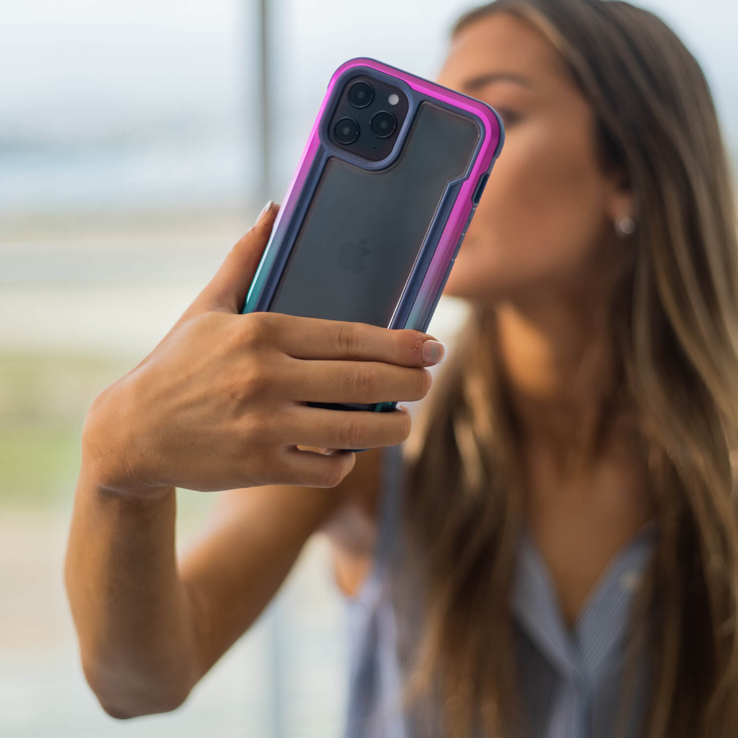 A woman is taking a selfie with her Raptic Shield case for iPhone 12 Pro Max.