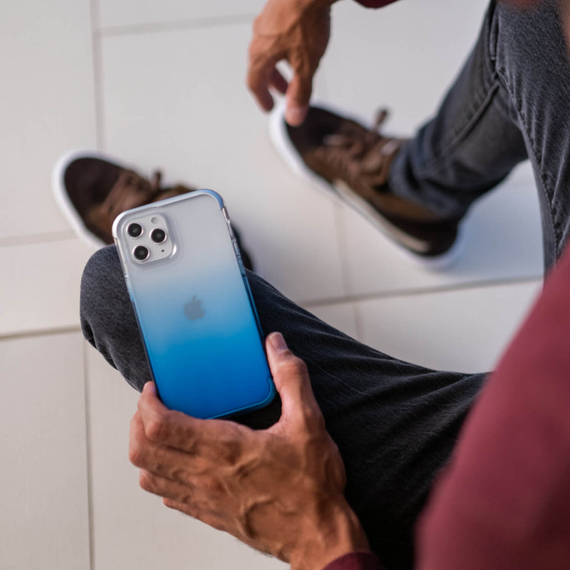 Showing a man holding a iPhone 12 Pro in a blue gradient Raptic Air case