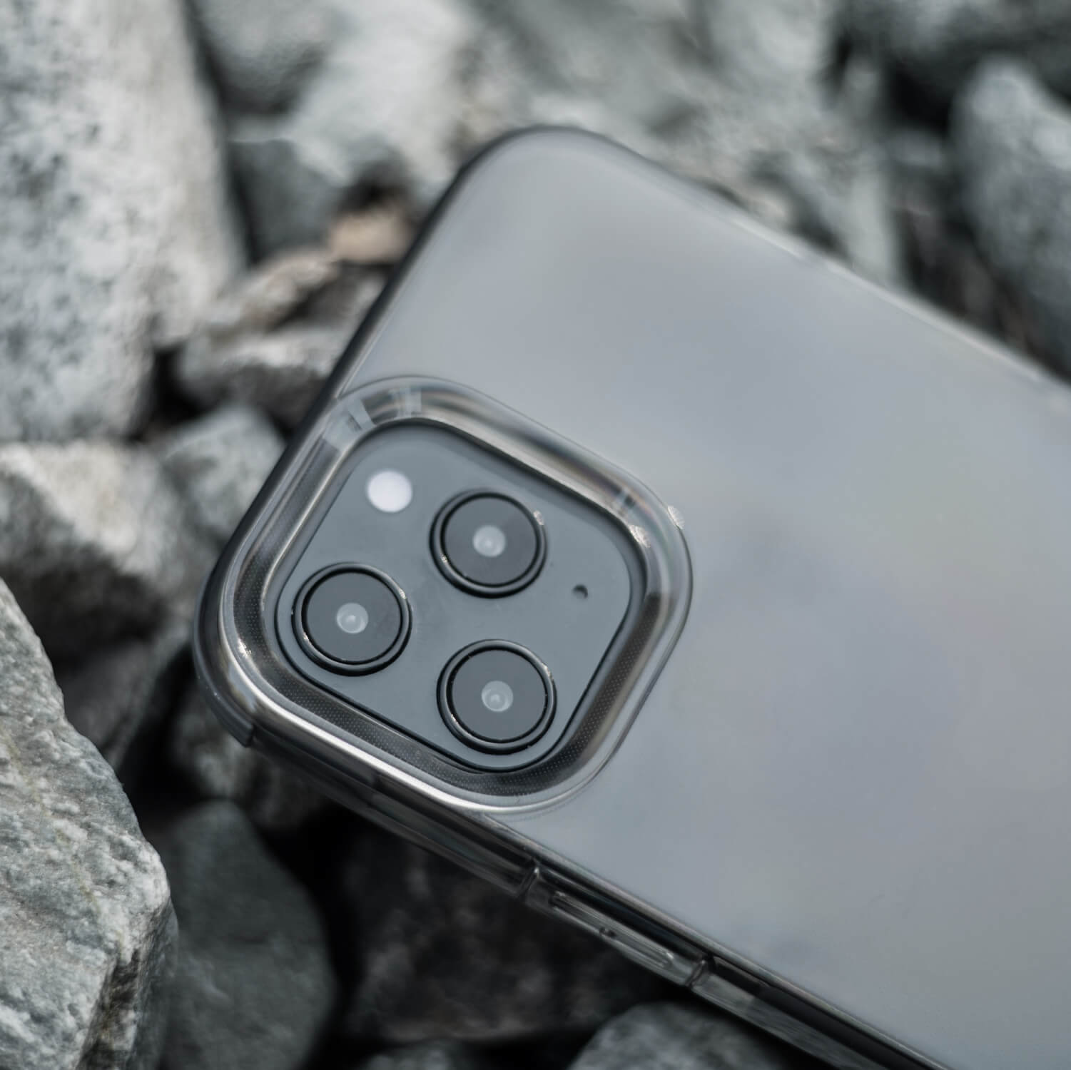 The iPhone 12 Pro Max is sitting on top of rocks with Raptic Clear case for drop protection.