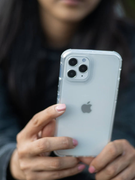 A woman holding an iPhone 12 with a Raptic Clear case.