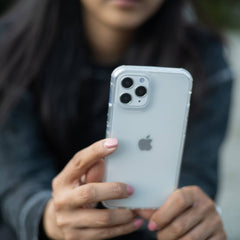 A woman holding an iPhone 12 Pro Max with a Raptic Clear case for drop protection.
