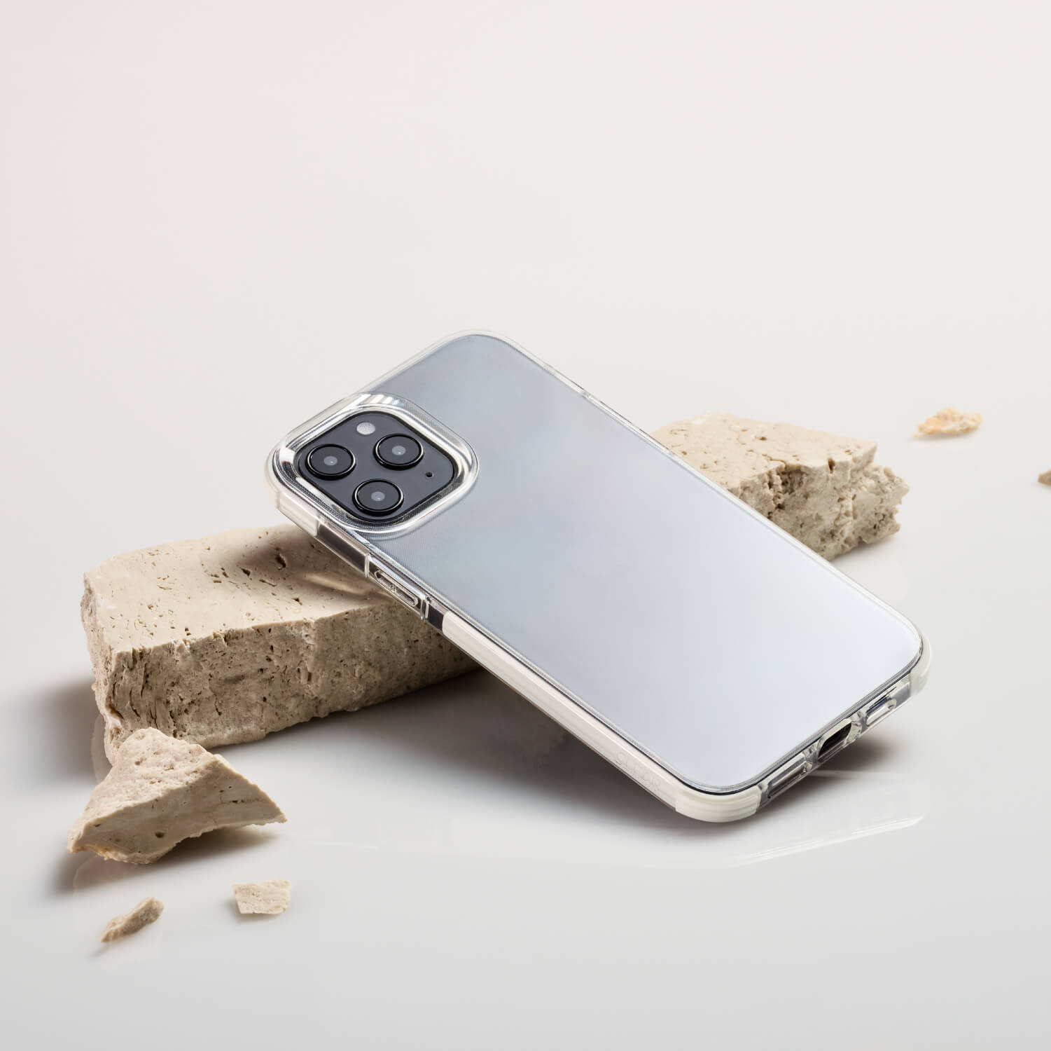 The Raptic Clear iPhone 12 Mini case is sitting on top of a piece of concrete, providing 2-metre drop protection.