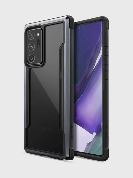 A Galaxy Note 20 Ultra fitted with the Raptic Shield case in black is displayed from both front and back against a plain light background. Designed by Raptic, this military-grade protective case offers wireless charging compatibility for enhanced durability and convenience while maintaining a sleek style.