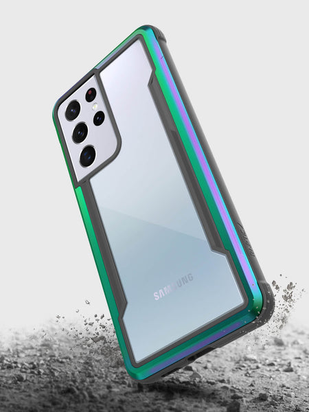 The Samsung Galaxy S21 Ultra encased in the X-Doria Raptic Shield Iridescent phone case hovers above a dusty surface, blending style with military-grade protection to ensure durability on any adventure.