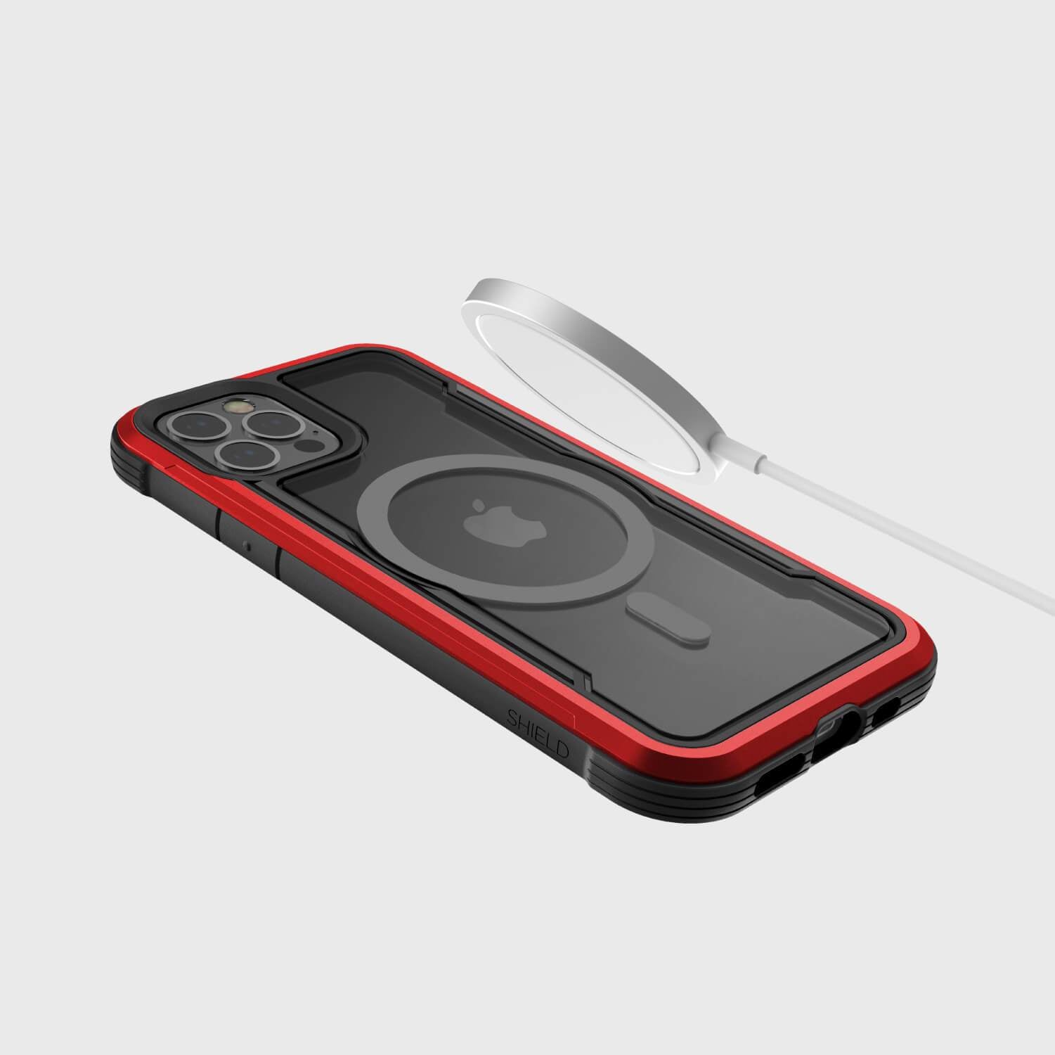 A red iPhone 12 Pro Max case - SHIELD PRO MAGNET by Raptic with a phone holder and MagSafe charger attached.