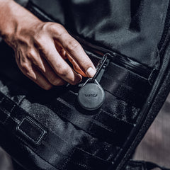 Apple AirTags encased in a Raptic Link case with carbines hanging off a stylish black bag