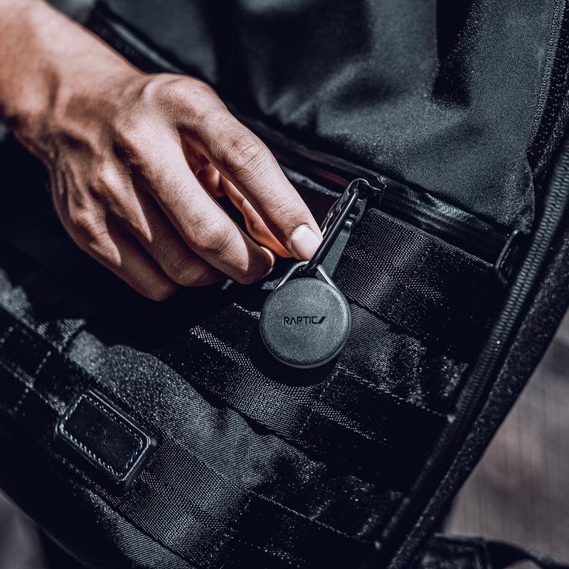Apple AirTags encased in a Raptic Link case with carbines hanging off a stylish black bag