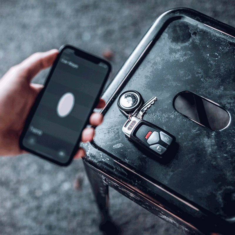 A man picking up Apple AirTags in a Raptic Link case to pair to his iPhone 