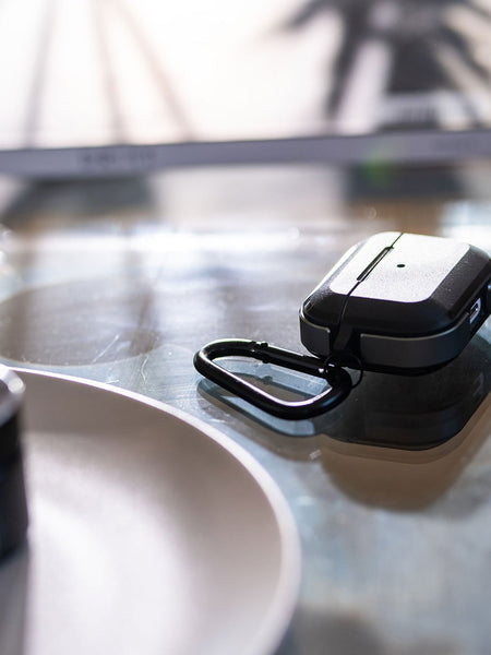 A pair of wireless earbuds, specifically the Apple AirPods Pro Case - TREK by Raptic, sitting on a table.