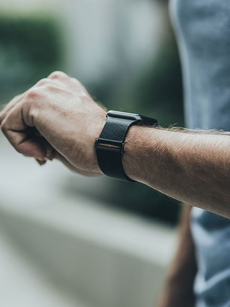 A man is wearing a stainless steel Raptic Apple Watch 42/44/45mm Band - MESH BAND on his wrist.