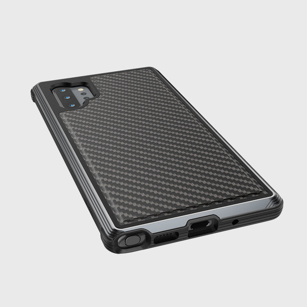 A Samsung Galaxy Note 10+ equipped with a Lux Black Carbon Raptic case rests on a white surface, highlighting its camera and charging port. This stylish case ensures military-grade drop protection for peace of mind without sacrificing aesthetics.