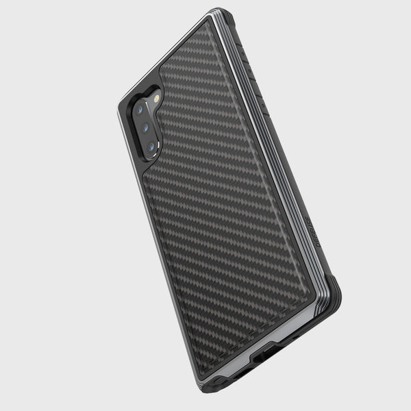 The Raptic Samsung Galaxy Note 10+ Case in Lux Black Carbon is shown from the back, displaying its dual cameras. It features a carbon fiber textured case with military-grade drop protection, a machined aluminum bumper, and remains wireless charging compatible, angled slightly left on a plain background.