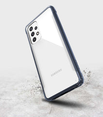 A Samsung Galaxy A53 smartphone with a Raptic Strong biodegradable, eco-friendly case standing upright on a concrete surface with a dynamic water splash effect near its base.