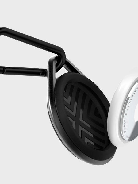 A black and white phone holder with an Apple AirTag Case - LINK from Raptic, equipped with a carabiner for easy attachment.