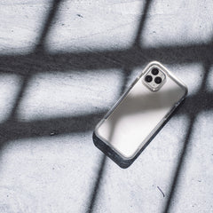 A white Raptic iPhone 13 Pro Case - AIR with 13 foot drop protection on a concrete floor.