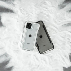 Two iPhone 11 Pros in sleek Raptic CLEAR cases lie on a powder-dusted surface, highlighting their durable design and wireless charging compatibility.