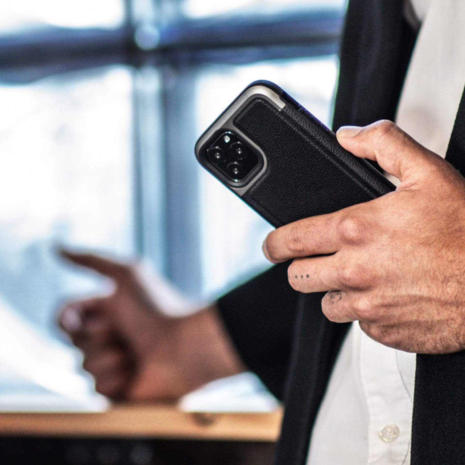 A man in a suit is holding a Raptic iPhone 11 Pro Case - Prime.
