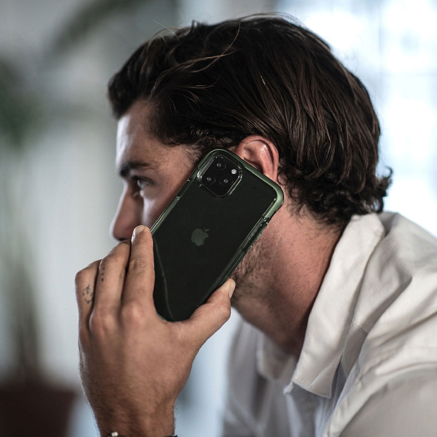 A man is talking on his Raptic iPhone 11 Case - AIR while wearing a green case.