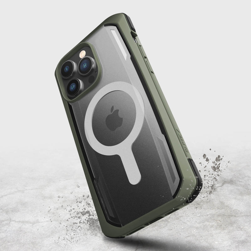 The iPhone 14 Pro Max Case ~ Secure by Raptic is a green rugged case with a translucent back featuring a circular MagSafe design. Made from biodegradable materials, it provides military-grade drop protection and is captured mid-air against a light background.
