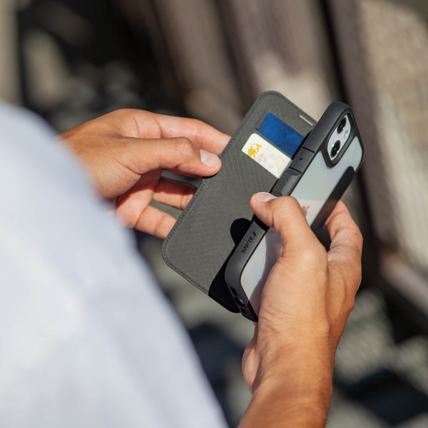 A person holding an iPhone 14 Pro Max by Raptic while holding an Urban Folio wallet.